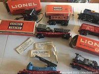 Wide view of multiple Lionel train cars, controllers, boxes and accessories on table