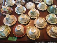 Overhead view of 15 assorted tea cup and saucer sets arranged on wooden table