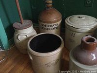 Front-row view showing butter churn with dasher, open crock, T. Eaton Co jug and Whiteway's Devon Cyder jug behind.