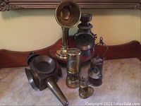 Overview of seven lanterns including tall brass reflector lamp, carbide lamps, signal head, and oil lanterns displayed on surface