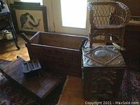 Overview showing wooden tea crate, fireplace bellows, brass-clad box, wicker child's chair and part of vintage sled