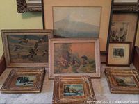 Group shot of all eight framed artworks on marble surface, showing size range and frame wear