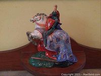 Front three-quarter view of knight on horse showing red cloak and horse’s front legs raised