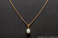 Full view of chain with opal pendant against black background