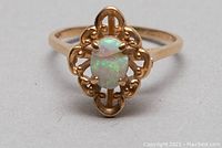 Front view of 14kt gold ring with opal stone in ornate filigree setting showing the crack in the opal.