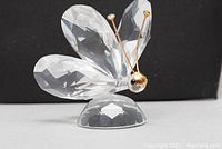 Front angled view showing large faceted crystal wings, gold wire antennae, and black bead eyes against a black background.