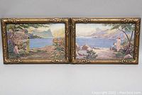 Pair of two horizontal framed prints showing lakeside landscapes with people, mounted in gold-tone decorative frames showing wear.