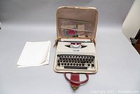 The Underwood Portable 18 typewriter inside the open carrying case, with original manual and some loose papers outside.