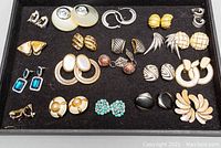 Photo showing all 20 pairs of vintage costume earrings arranged on black velvet display tray.