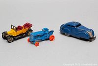 Three vintage toy vehicles including yellow Daimler Y-13, blue Fordson tractor, and blue SCHUCO windup car