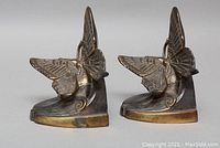Side view of the pair of spelter metal butterfly bookends showing detailed butterfly wings and geometric bases with aged patina.