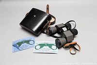 Overall set of Mirador binoculars, leather case, instruction manual, and rain-guard in a single frame