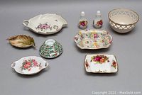 Full view of the lot showing various ceramic and porcelain bowls, dishes, and salt and pepper shakers with floral and holiday motifs