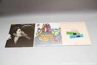 Three vinyl album covers displayed flat: John Lennon & Yoko Ono 'Double Fantasy', The Beatles 'Yellow Submarine', and The Beatles 'At The Hollywood Bowl'.