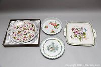 Four porcelain dishes: one butterfly serving dish in box, three pie plates with floral and fruit designs.