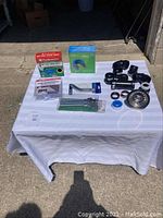Wide view of plumbing items laid out on table, showing pipe fittings, drain parts, adhesive sealer, and sealing tape.