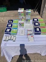 Overview of lot items arranged on white cloth showing multiple boxes of outlets, switches and faceplates, unopened and new in box.
