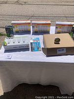 Lot of new LED bulbs and accessories displayed on a table outdoors. Includes multiple packs of 10-pack 13W bulbs, a box of GU10 spotlight bulbs, and smaller packages of bulbs and accessories.