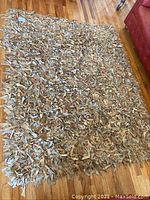 Full view of rectangular brown and beige leather shag rug on hardwood floor.