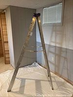 Aluminum step ladder in open position showing size and paint wear