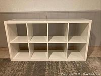 Front view of white rectangular shelf with 8 compartments, glossy finish visible
