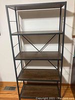 Front view of the 5-shelf bookcase showing all wooden shelves and metal frame with cross braces on the back.