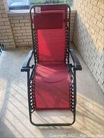 Front view of the raspberry colored zero gravity chair showing padded headrest, black armrests, and fabric seat with black lacing on the sides