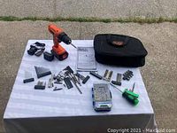 Full contents laid out on a table including drill, charger, carrying case, drill bits, screwdriver bits, and manual.