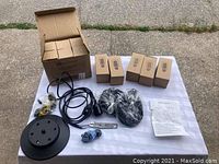 Full set of 11 Edison bulbs in individual boxes and chandelier fixture components including ceiling mount base, cords, and wiring laid out on a white cloth.