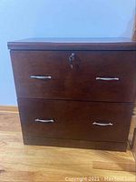 Front view of the dark brown wooden 2 drawer file cabinet showing silver handles and central lock with keys inserted.