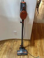 Front view of Shark Rocket upright vacuum on wooden floor, showing handle, body and cleaning head.