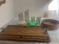 Photo showing all items from a side angle on a table, including stacks of ramekins, glass containers with green lids, white ceramic cheese pot, wooden serving tray, and maple wood bowl.
