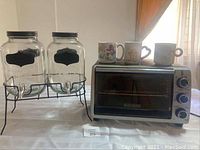 Overview of the toaster oven, two spouted mason jars on metal stands, and three Care Bear mugs.