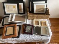 Full lot laid out on table including 18 picture frames and wicker basket