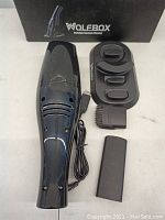 Wolebox handheld vacuum cleaner with visible scratches, charging cord and three attachments on white surface.
