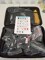 Photo of black zippered carrying case with mesh pockets holding multiple accessories for action cameras in sealed plastic bags along with a printed inventory sheet.