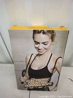Front of boxed electronic skipping rope showing a woman holding the skipping rope and text 'Electronic Counting Skipping Rope'.