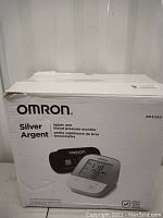 Box front showing Omron Silver upper arm blood pressure monitor image and model BP5250.