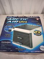 Front view of the Artic Air Ultra evaporative air cooler box, highlighting features like 3-speed control, LED night light, and 2X cooling power.