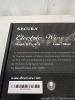 Photo of the front of the box showing the Secura Electric Wine Opener model KP1-36N2 features including cordless, rechargeable, stainless steel, blue LED lights, and foil cutter.