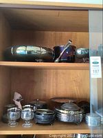 Wooden shelf with assorted silver plated serveware including oval footed bowl, compote bowls, gravy set, openwork coaster, cordial glasses and pewter boxes.