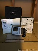 Photo showing RadarGolf handheld device, black carrying case, instruction manual, and multiple boxes of golf balls.