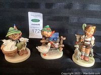 Photo of all three Hummel figurines together on black background showing Playmates, Goat Herder, and Barnyard Hero