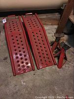 Pair of red steel 36-inch car ramps with multiple round traction holes, laid out on the floor.