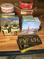 Vintage tins, hat box, and California, Wisconsin license plates on tabletop.