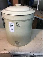 Full view of the beige crock with lid showing height and general shape.