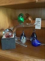 Overall lot showing Murano birds on clear glass branch, two glass penguins, and paperweights.