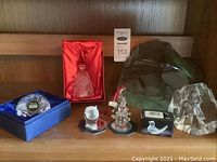 Shelf display of all the crystal items: Waterford clock, bell, Swarovski figurines (owl and clown), crystal piano, etched face, and buffalo decorations.