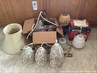 Photo showing the full lot of vintage lighting including painted lamp, sconces, lampshades, and wiring in cardboard box.