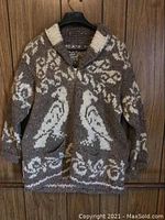 Full front view of brown-gray and white knitted sweater with shawl collar, zip closure, pockets and bird motifs